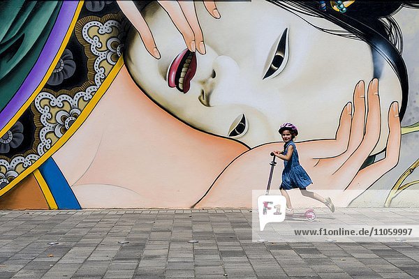 Buntes Graffiti mit japanischem Motiv an einer Hauswand  kleines Mädchen fährt auf einem Kinderroller  Würzburg  Bayern  Deutschland  Europa
