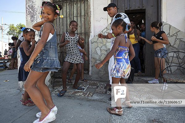 Local children dancing with their dance instructor in front of a dancing school in the street  Santiago de Cuba Province  province of Santiago de Cuba  Cuba  North America