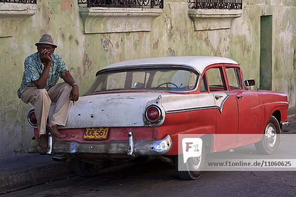 Kubanischer Taxifahrer sitzt auf Oldtimer-Taxi  Santiago de Cuba  Provinz de Santiago de Cuba  Kuba  Nordamerika
