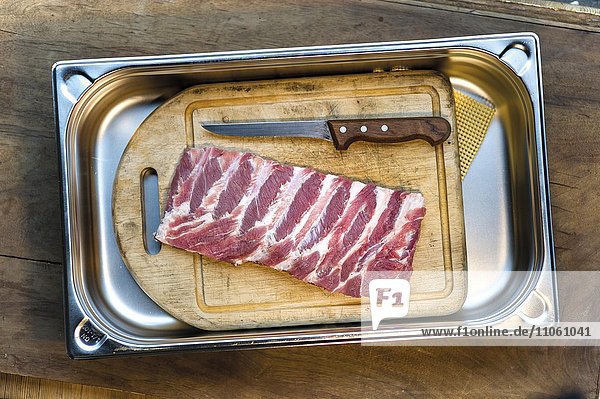 Raw Spareribbs  ribs  lying on wooden cutting board with knife