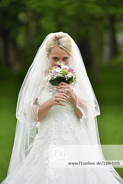 Braut mit Brautkleid und Schleier riecht an Brautstrauß  Deutschland  Europa