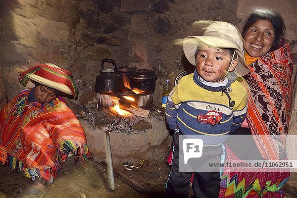 Indio family at the fireplace in their hut Andes Lares near Cusco Peru South America