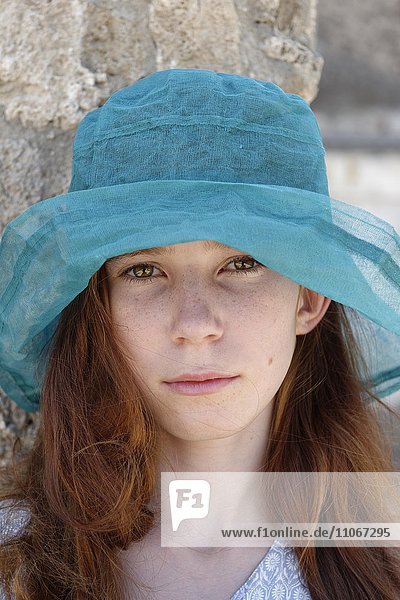 Red-haired girl with a turquoise sun hat looking seriously  portrait  Italy  Europe