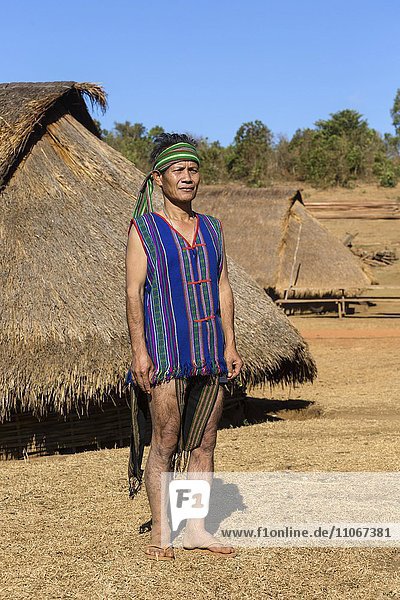Mann in traditionellem Kostüm vor Phnong Haus  Ethnische Minderheit  Pnong  Bunong  Senmonorom  Sen Monorom  Provinz Mondulkiri  Kambodscha  Asien