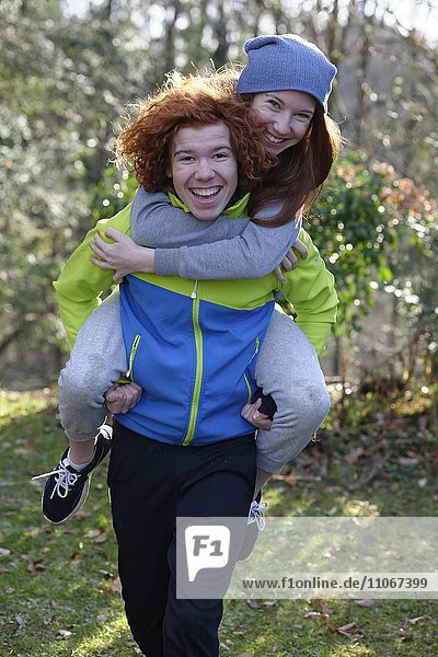 Young girl carrying his sister on his back  piggyback  redheaded siblings  Bavaria  Germany  Europe