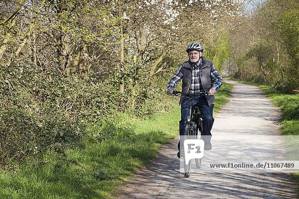 Senior mit Fahrradhelm fährt Fahrrad  Nordrhein-Westfalen  Deutschland  Europa