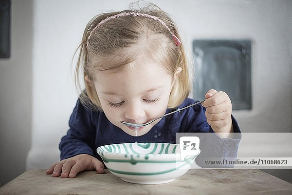 Kleines Mädchen isst Müsli aus einer Schüssel  Oberbayern  Deutschland  Europa