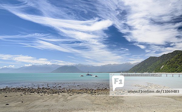 Fishing boat at pier and turquoise sea  cloudy sky  Jackson Bay  West Coast  Tasman  South Island New Zealand