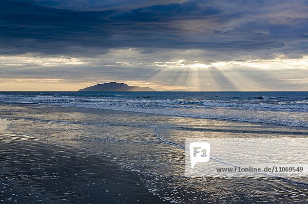 Abendstimmung am Sandstrand  Wellen  Sonnenstrahlen mit dramatischem Wolkenhimmel  Ostküste  Nordinsel  Neuseeland  Ozeanien