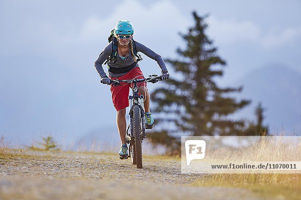 Mountainbikerin mit Helm fährt auf einem Schotterweg  Mutterer Alm bei Innsbruck  Tirol  Österreich  Europa