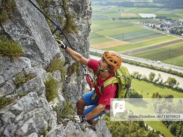Climber with orange helmet climbing the via ferrata  Martin Wall  Zirl  Innsbruck  Tyrol  Austria  Europe