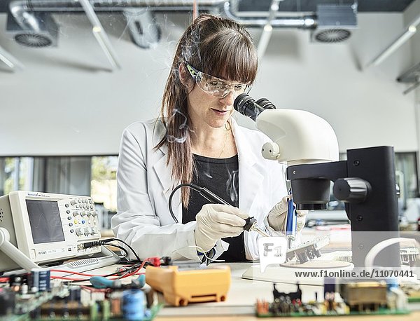 Technikerin  Frau 20-25 Jahre  mit weißem Laborkittel lötet eine Platine in einem Elektronik Labor  Wattens  Innsbrucker Land  Tirol  Österreich  Europa