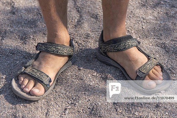 Füße eines Mannes in Sandalen  steht im Sand