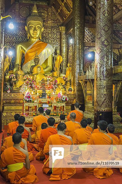 Buddhist monks praying in the temple Wat Xieng Thong  Luang Prabang  Laos  Asia