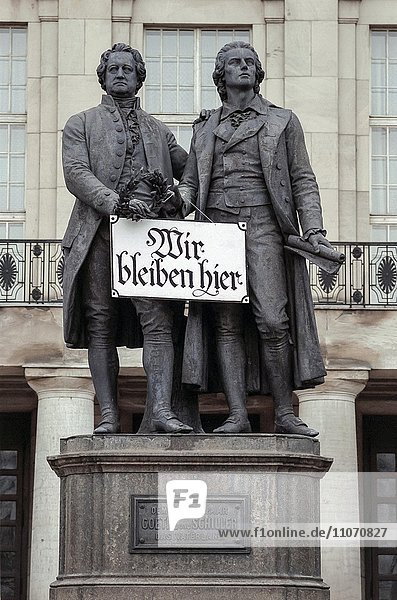 Goethe and Schiller monument with sign Wir bleiben hier or We stay here  historical photo  German reunification November1989  Weimar  Thuringia