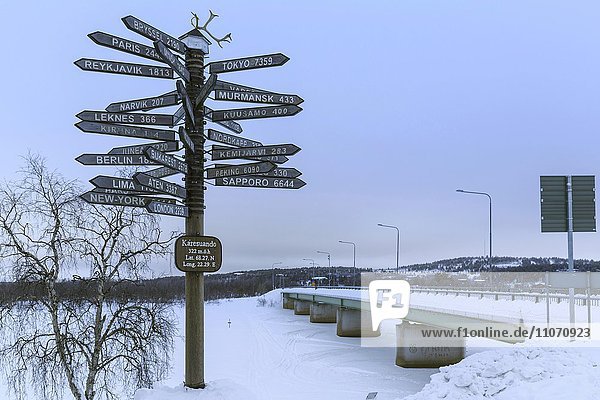 Signpost pointing in all directions  bridge across River Munio behind  Karesuando  Norrbotten County  Sweden  Europe
