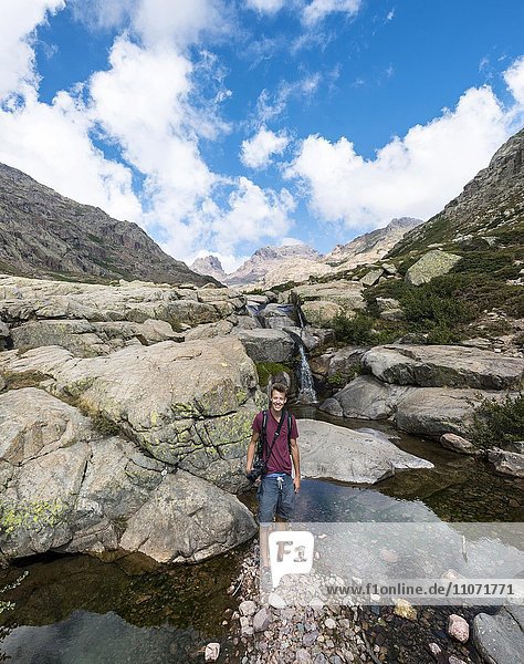 Young man standing at a pool with a small waterfall in the mountains  river Golo  Nature Park of Corsica  Parc naturel régional de Corse  Corsica  France  Europe