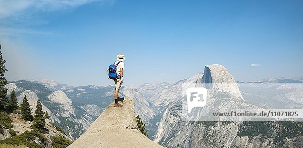 Young man standing on ledge  looking at the Half Dome  view from Glacier Point  Yosemite National Park  California  USA  North America