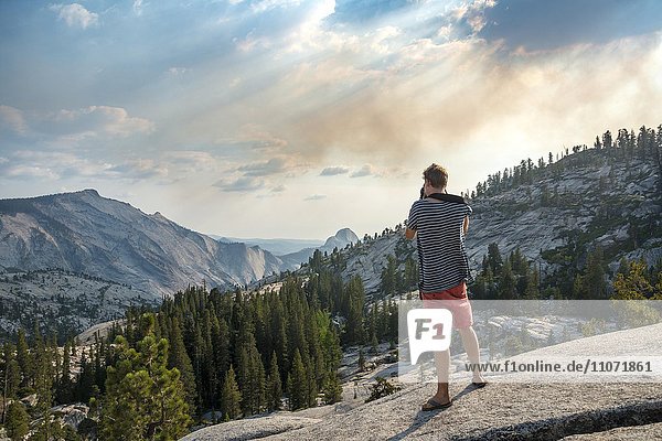 Junger Mann  Tourist fotografiert  Ausblick in die High Sierra  Olmsted Point  Yosemite Nationalpark  Kalifornien  USA  Nordamerika