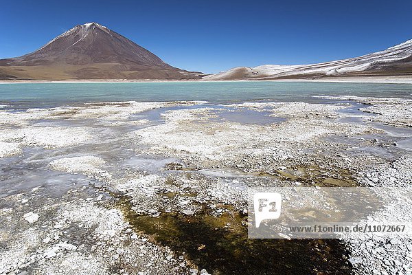 Laguna verde with deposits of borax on the shore and snow on the mountains  near Uyuni  Altiplano  border Bolivia  Chile  South America