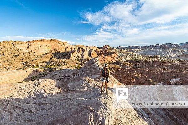 Touristin  Wanderin an der Fire Wave Sandsteinformation  dahinter Felsformation Sleeping Lizard  Valley of Fire State Park  Nevada  USA  Nordamerika