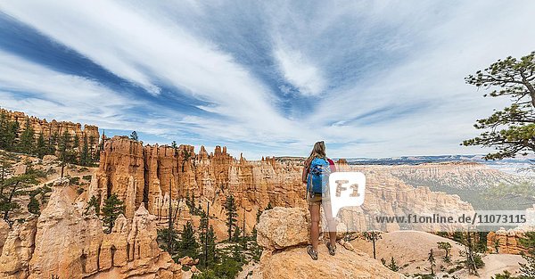 Wanderin mit Rucksack in bizarrer Landschaft  rötliche Felslandschaft mit Hoodoos  Sandsteinformationen  Bryce Canyon Nationalpark  Utah  USA  Nordamerika