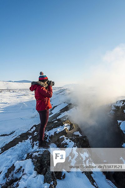 Frau steht an Kontinentalspalte zwischen Nordamerikanischer und Eurasischer Platten  und fotografiert  Mittelatlantischer Rücken  Grabenbruch  Krafla  Mývatn  Nordisland  Island  Europa