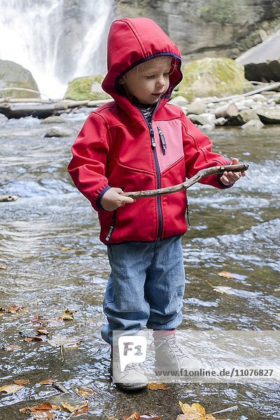 Toddler playing with a stick on a creek  Höchfall in Teufen  Switzerland  Europe