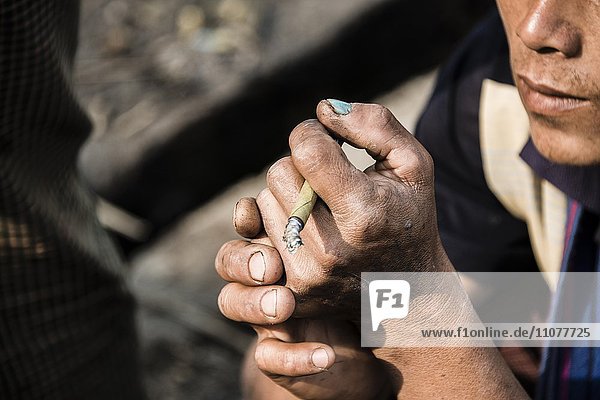 Mann raucht  hält Cigarillo in der Hand  Cheroot-Zigarre  Nampan  Inle Lake  Inle See  Shan Staat  Myanmar  Asien