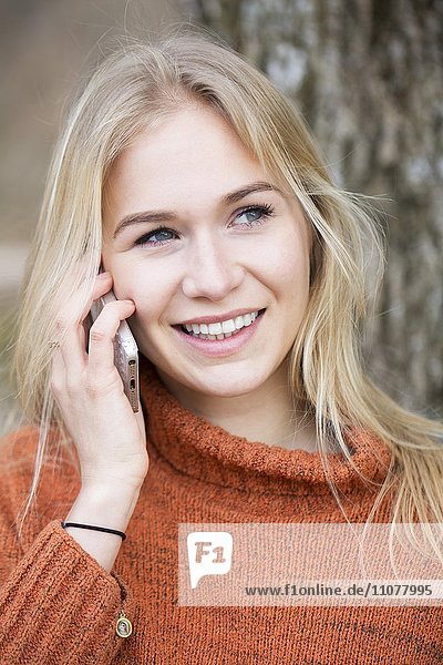 Blondes junge Frau telefoniert mit einem Handy