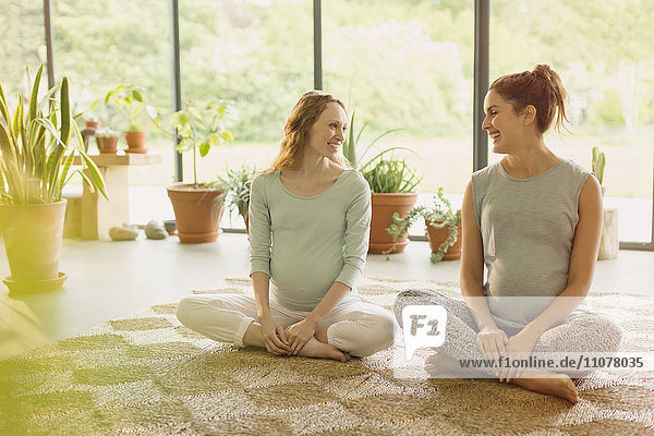 Lächelnde schwangere Frauen sprechen auf dem Teppich
