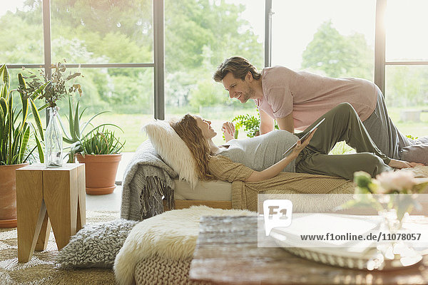 Affectionate pregnant couple laying on chaise