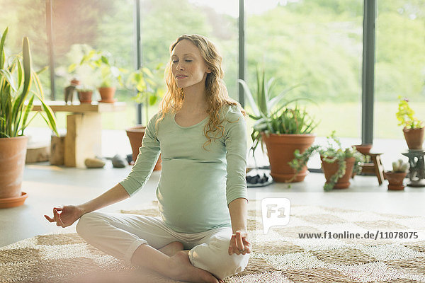 Schwangere Frau beim Meditieren in Lotusstellung