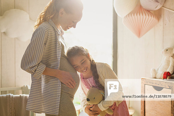 Tochter hört schwangeren Muttermagen im Kinderzimmer zu