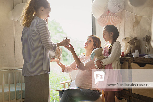 Pregnant woman receiving gift in nursery