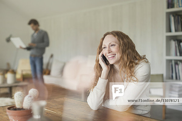 Smiling woman talking on cell phone at dining table