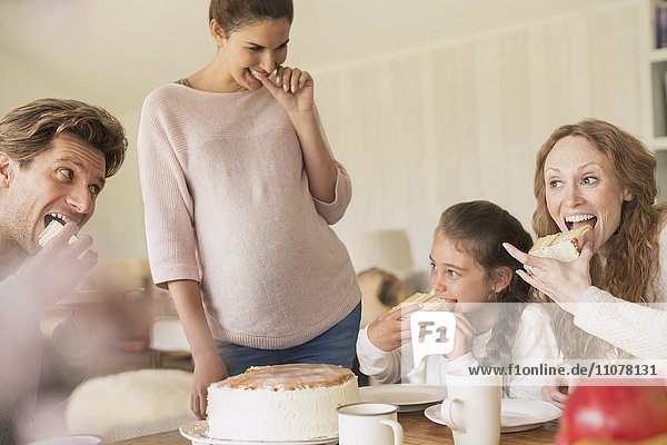 Enthusiastic family eating cake at table