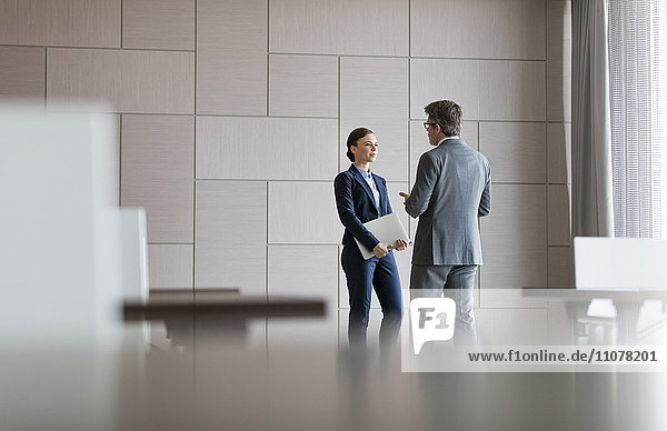 Businessman and businesswoman talking in conference room