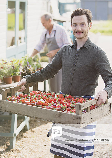Portrait lächelnder Pflanzenzüchter mit Erdbeerkiste