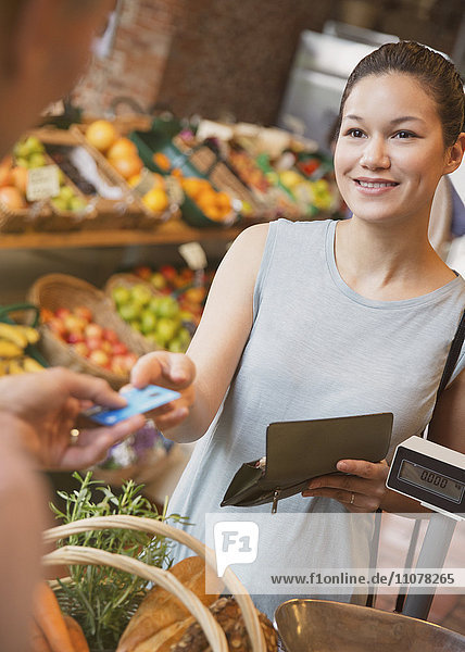 Frau bezahlt mit Kreditkarte an der Kasse des Lebensmittelgeschäfts
