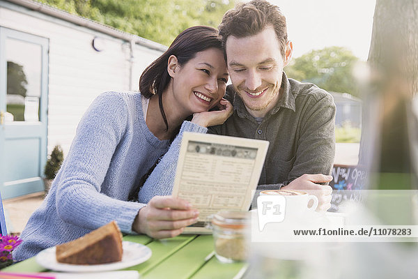 Lächelndes Paar schaut auf die Speisekarte im Outdoor-Café