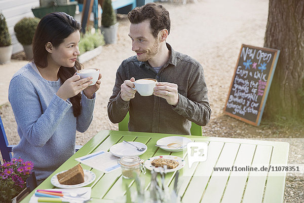 Couple enjoying cappuccinos and dessert an outdoor cafe