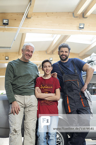 Portraits lächelnde Mehrgenerationen-Mechanikerfamilie in der Kfz-Werkstatt