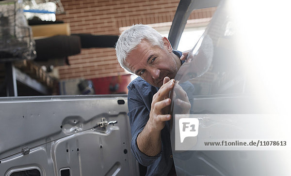 Mechaniker bei der Prüfung der Fahrzeugverkleidung in der Kfz-Werkstatt