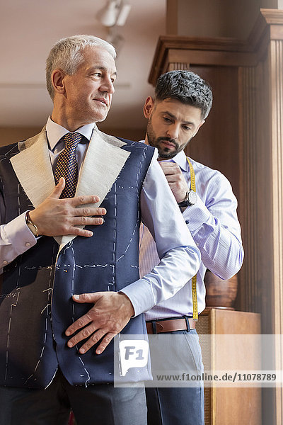 Tailor fitting businessman for suit in menswear shop