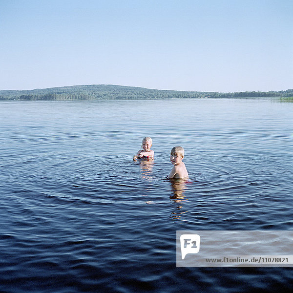 Zwei Kinder schwimmen im See