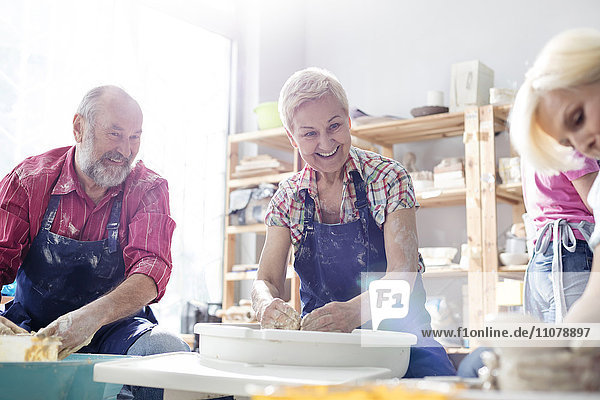 Lächelndes Seniorenpaar mit Töpferscheiben im Studio