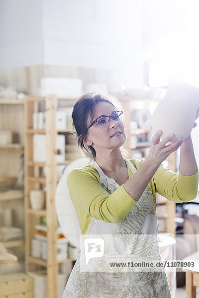 Reife Frau untersucht Keramikvase im Atelier