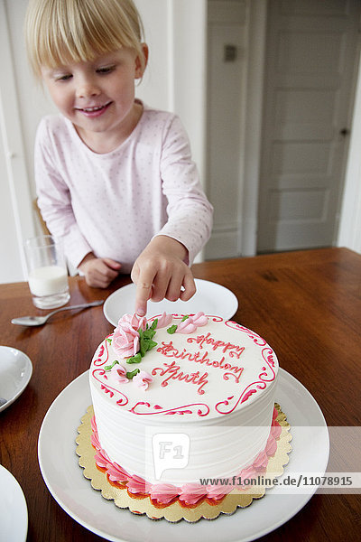 Girl touching birthday cake
