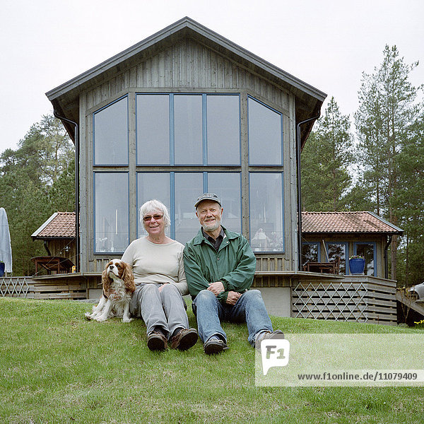 Älteres Paar im Gras sitzend  Porträt  lächelnd